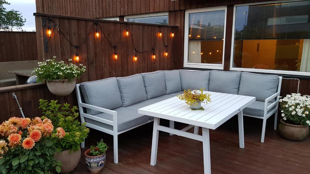 a patio with a couch and a table and flowers at 3 bedrooms home with nice terrace in Stavanger