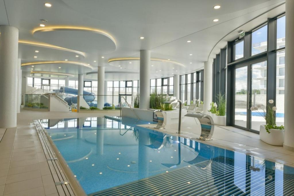 a large swimming pool in a building with a pool at Polanki Aqua Apartament LUNA in Kołobrzeg