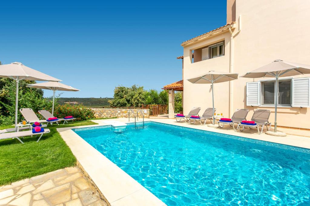 einen Pool mit Stühlen und Sonnenschirmen neben einem Haus in der Unterkunft Villa Korini by Villa Plus in Achlades