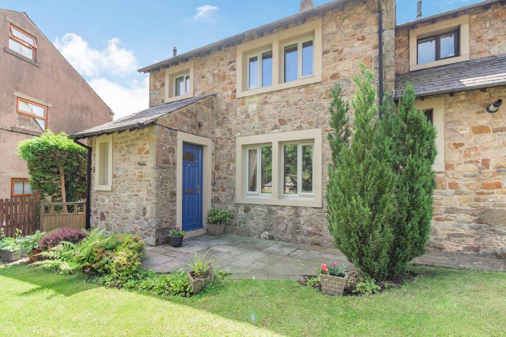 a brick house with a blue door and a yard at Springfield Cottage in Chipping