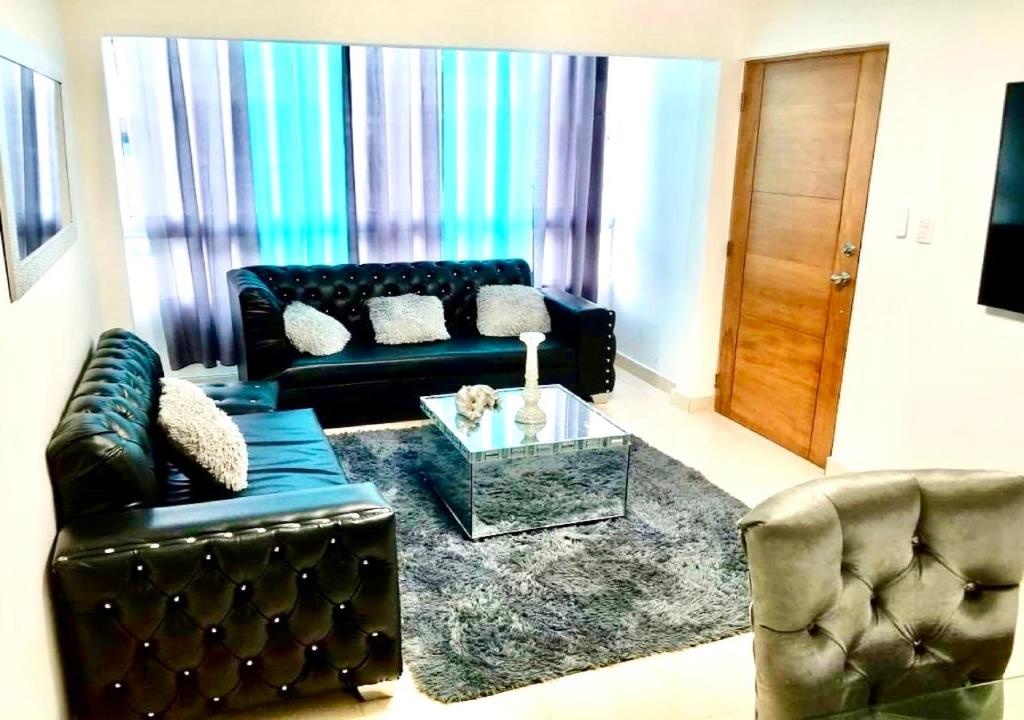 a living room with a black leather couch and a table at Bello y comodo apartment , residencial con piscina, seguridad las 24 Horas in Licey al Medio