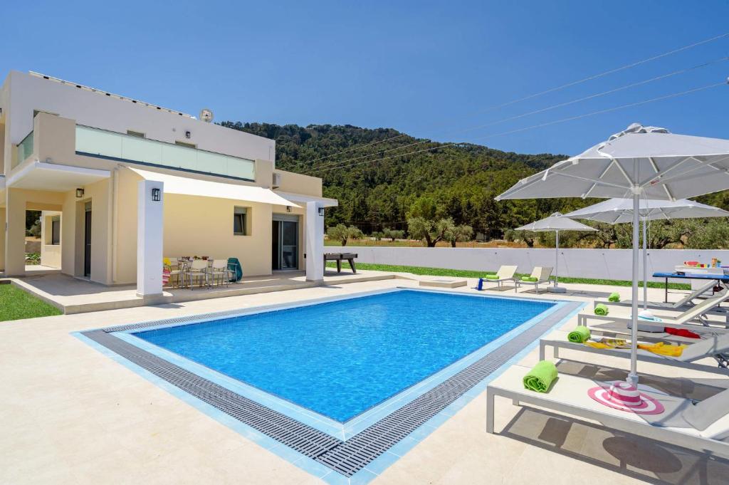 eine Villa mit einem Pool und Gartenmöbeln in der Unterkunft Villa Paleos Sunset by Villa Plus in Ialyssos