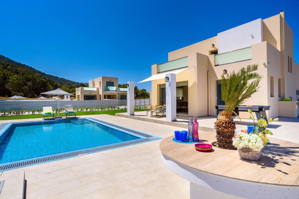 una villa con piscina di fronte a un edificio di Villa Paleos Evergreen by Villa Plus a Ialyssos