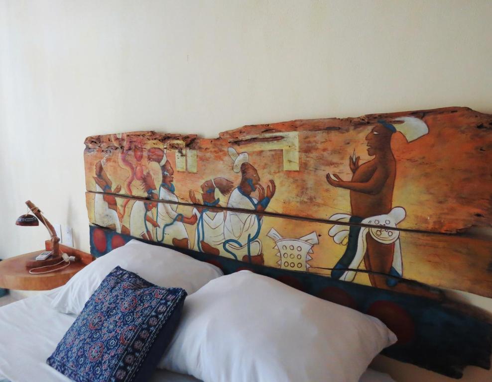 a bed with a painting on the wall at Art Maya Rooms in Holbox Island