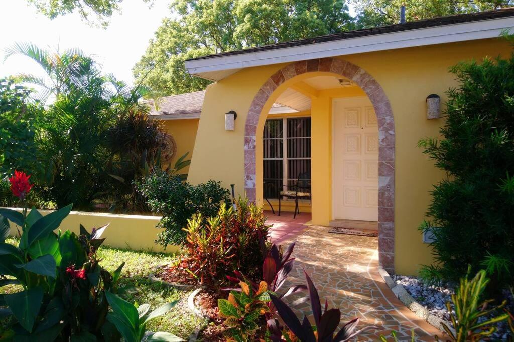 a yellow house with an archway in a garden at Comfortable, Sunny, Quiet Neighborhood in Port Richey