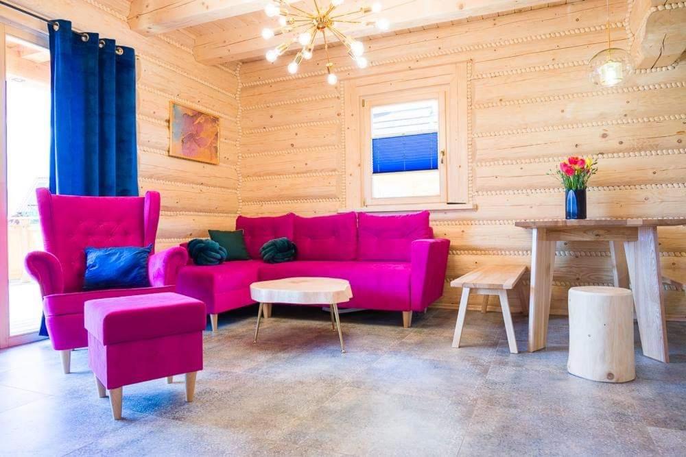 sala de estar con sofá rosa y 2 sillas en Beskid Wood Houses en Istebna