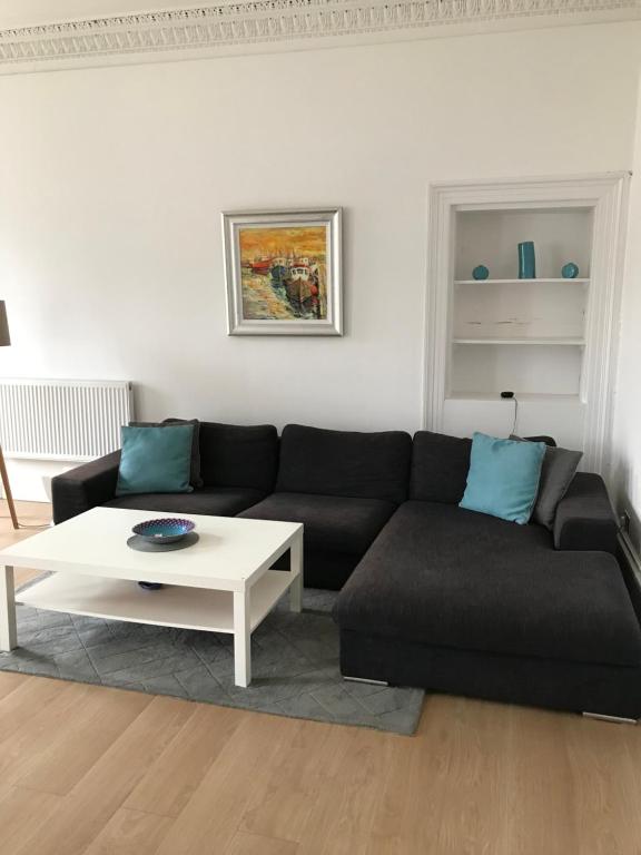 ein Wohnzimmer mit einem schwarzen Sofa und einem weißen Tisch in der Unterkunft Apex Buccleuch Street Apartment in Glasgow