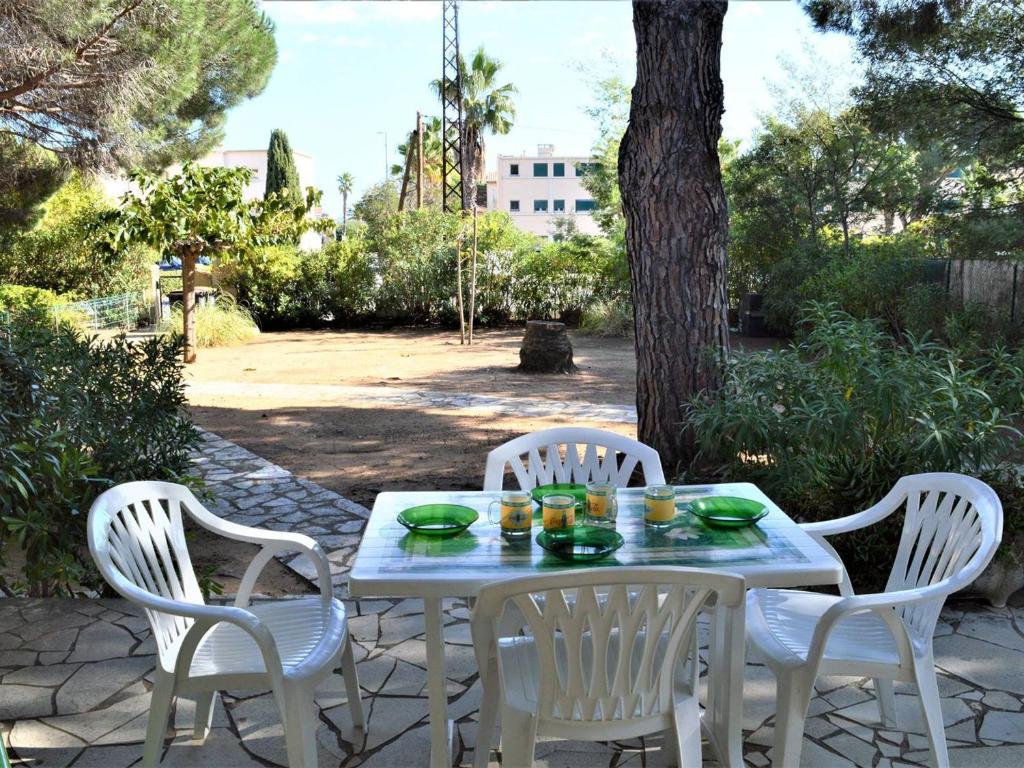 une table blanche et quatre chaises assises sur une terrasse dans l'établissement Appartement T2 pour 4 personnes, proche plage et commerces, jardin privé, parking, animaux acceptés - FR-1-226B-111, à Cavalaire-sur-Mer