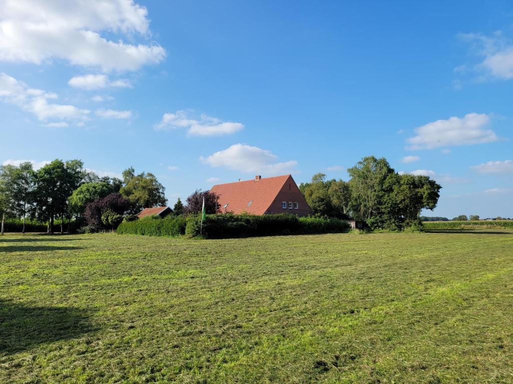 a large field with a red house in the distance at Ferienbauernhof De Slaaphoeve in Emlichheim