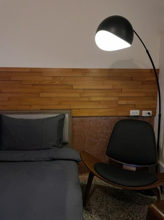 a bedroom with a bed and a black lamp and a chair at PY Homestay in Tainan