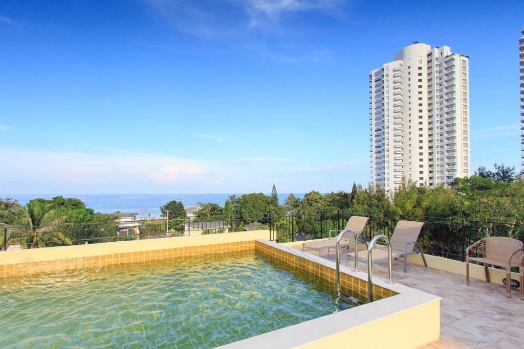 una piscina con sillas y un edificio en De Pastel Hua Hin, en Hua Hin