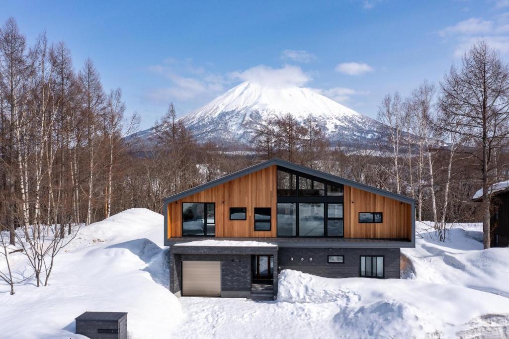 a house in the snow with a mountain in the background at Shion in Kutchan