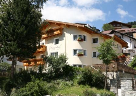 a large white building on a hill with trees at Appartements Plattlerhof in Serfaus