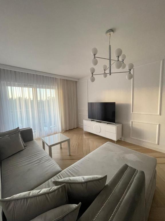 a living room with a couch and a tv at Luksusowy Apartament na Wydmach Międzywodzie in Międzywodzie