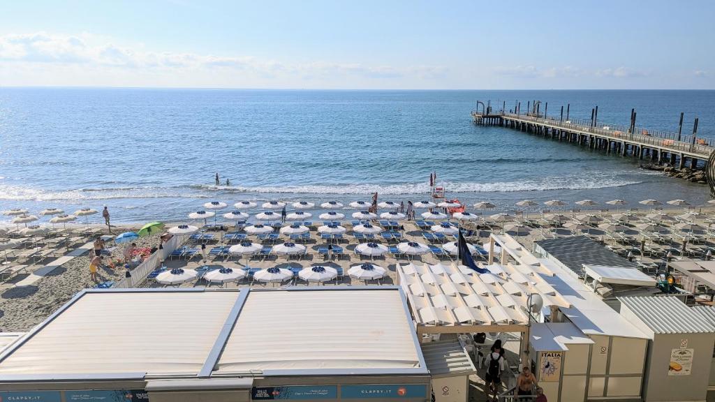 une plage avec des chaises, des parasols et une jetée dans l'établissement Appartamenti sul mare Alassio, à Alassio