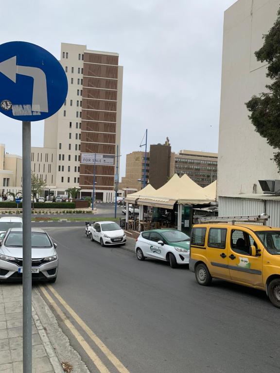 a yellow van driving down a street with parked cars at White Arches Modern Beautiful studio in Limassol