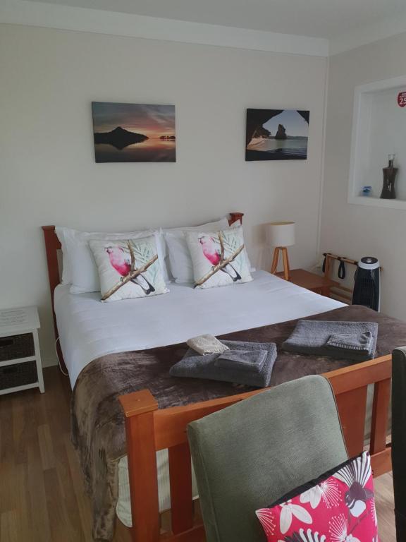 a bedroom with a large white bed with a chair at Bluewater Studio in Tairua