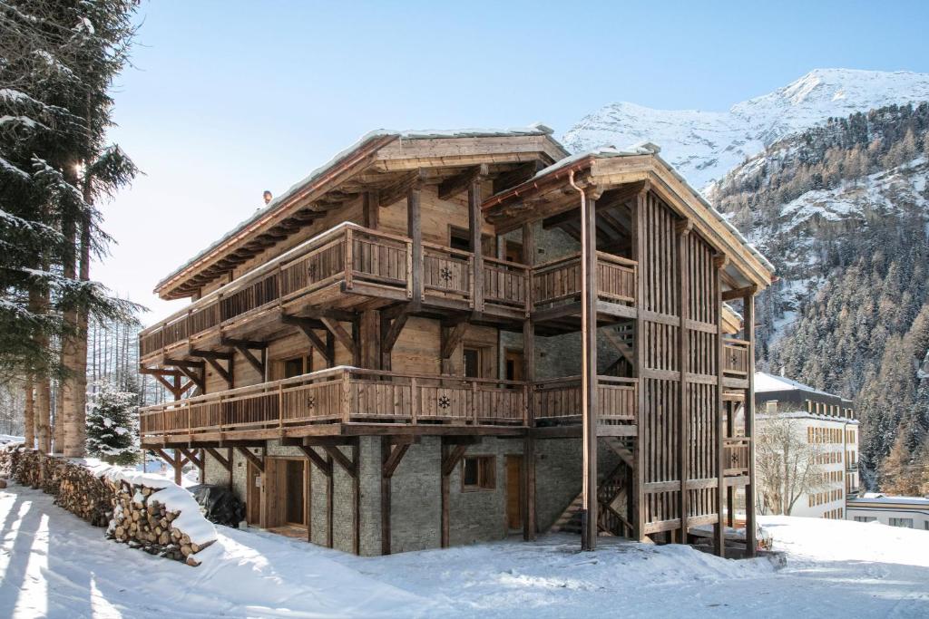 una gran casa de madera en la nieve con una montaña en Polaris appartement 2, en Zinal