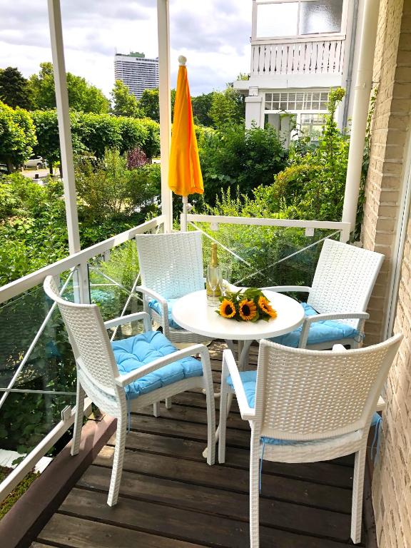 a porch with a table and chairs and an umbrella at Apartment Kaiserperle mit Balkon direkt am Strand in Lübeck