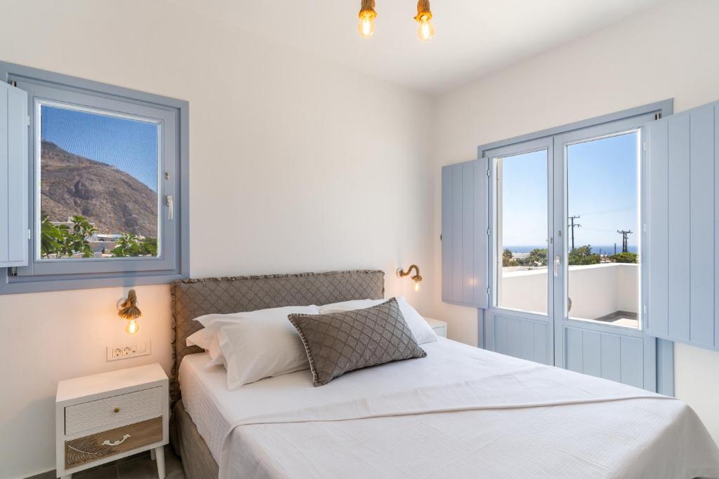 a white bedroom with a bed and two windows at SantoRossa Luxury Villas in Emporio Santorini