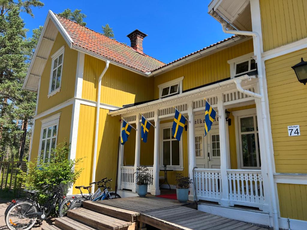 une maison jaune arborant des drapeaux bleus sur la terrasse couverte dans l'établissement Hedenstugan B&B Hotel, à Bergby