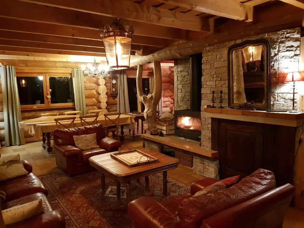 a living room with leather furniture and a fireplace at Magnifique chalet en rondins avec sauna - Vercors in Villard-de-Lans