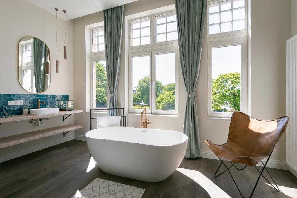 uma casa de banho com uma grande banheira branca e uma cadeira. em Fantastisch Herenhuis ENSEMBLE em Ieper