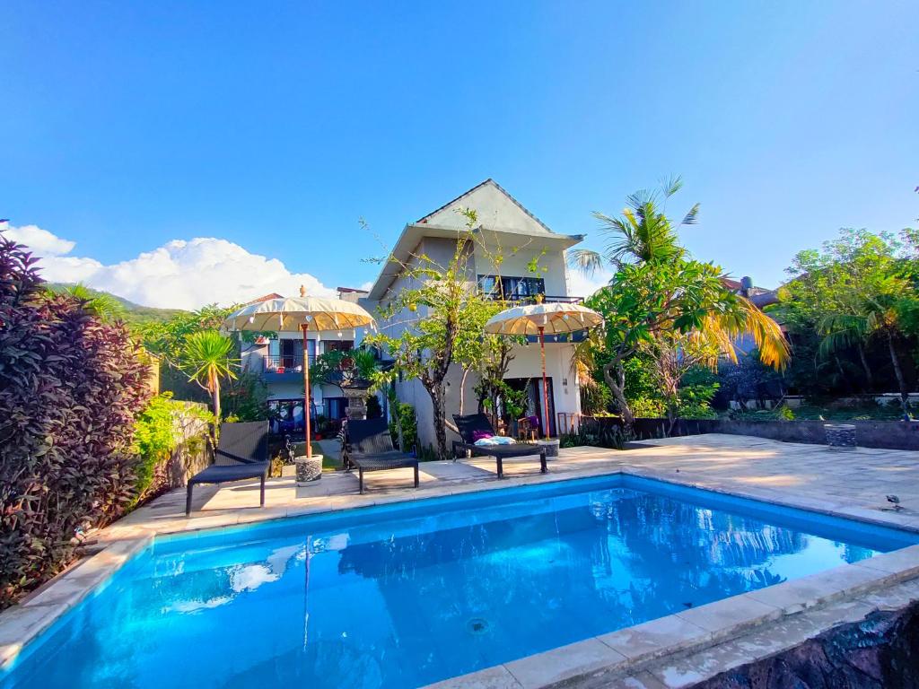 a villa with a swimming pool in front of a house at Bali Yogi in Amed