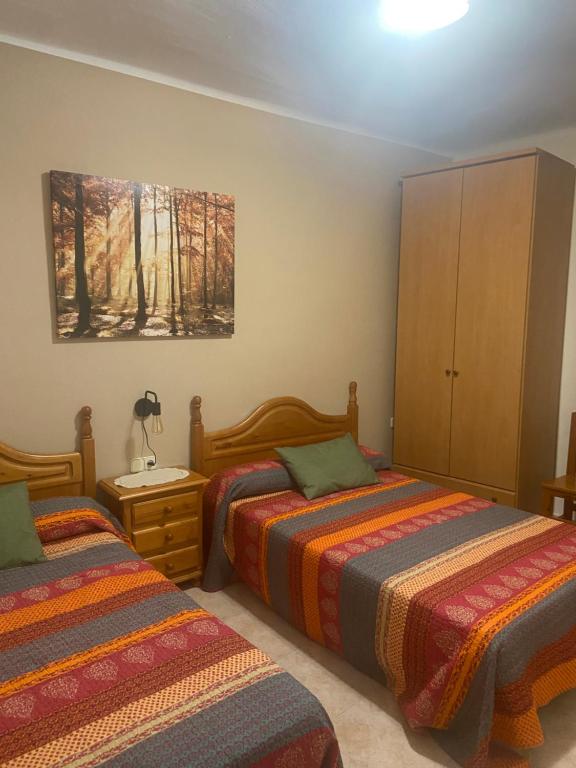 a bedroom with two beds and a painting on the wall at Allotjament rural Casa Milagros in Barruera