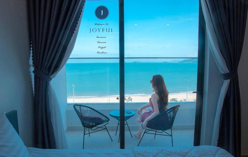 una donna seduta in una stanza con vista sull'oceano di TMS QUY NHƠN - SUIN Luxury Aparment a Quy Nhon