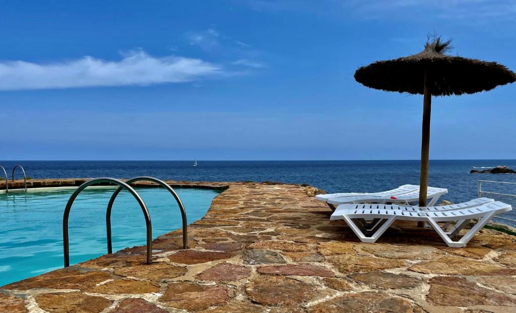 zwei Stühle und ein Sonnenschirm neben einem Pool in der Unterkunft Cap Sa Sal - Sa Roca 3 in Begur