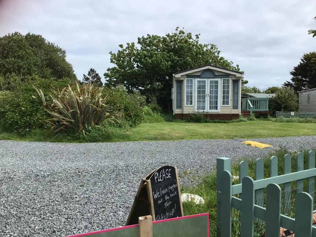 a small house with a sign on the side of a gravel road at lovely holiday home nr Kynance Cove in Lizard