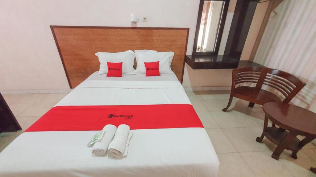 a bedroom with a large bed with two red pillows at RedDoorz At Pujon Malang in Batu