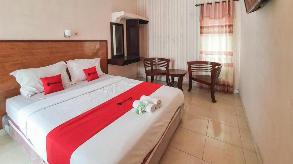 a bedroom with a large bed with red and white sheets at RedDoorz At Pujon Malang in Batu