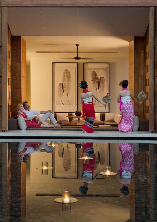 a group of people standing in a living room with their reflections at Anantara Chiang Mai Resort in Chiang Mai