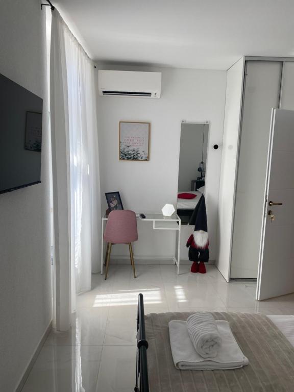 a white living room with a table and a pink chair at Litore in Pula