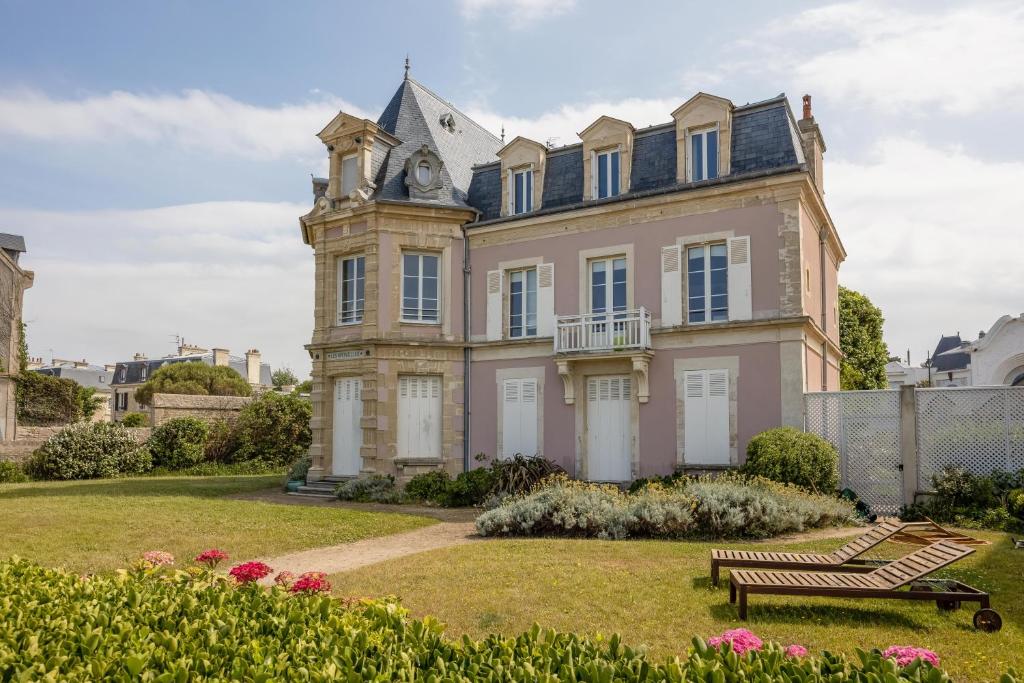 uma casa velha com uma torre de relógio em cima em Villa Les Hirondelles - Appartement avec Jardin Front de mer em Saint-Aubin-sur-Mer