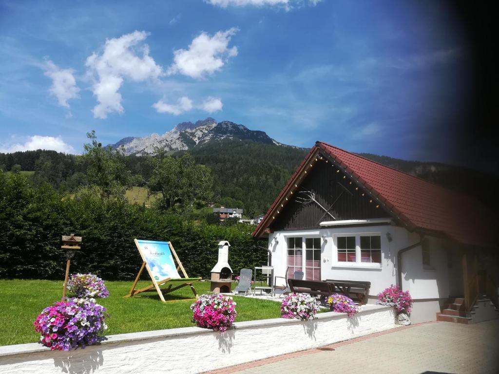 a small white house with flowers in the yard at Tischlmühle Appartements & mehr in Gröbming