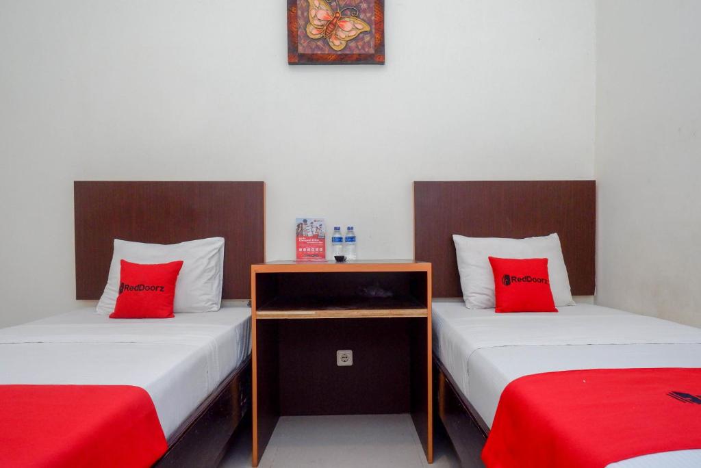 2 camas con almohadas rojas en una habitación en RedDoorz Syariah At Namira Hotel, en Yogyakarta