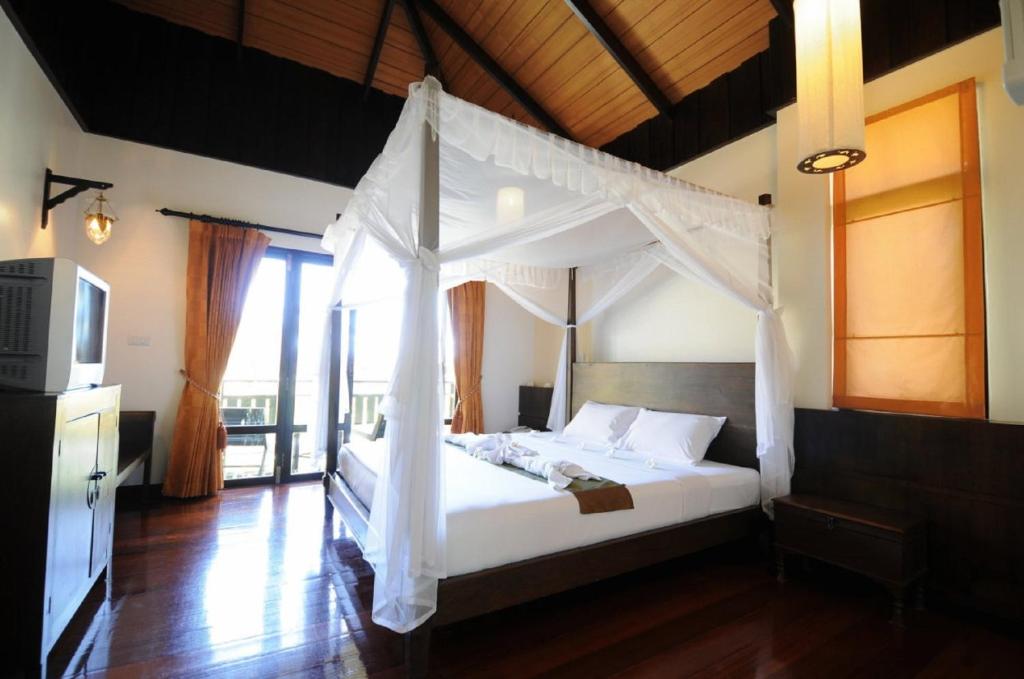 Kao Tao Villa Beach Resort في خاو تاو: غرفة نوم بسرير أبيض مع مظلة