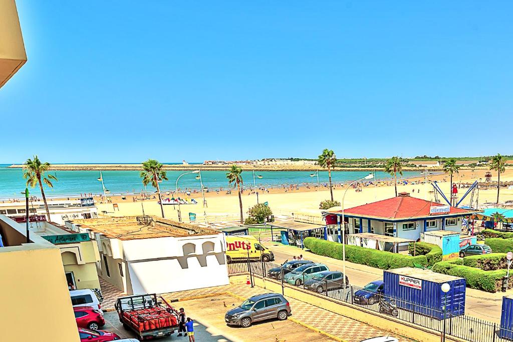 una vista de una playa con coches aparcados en un aparcamiento en Ocean View Beach Apartment with Pool & Balconies en El Puerto de Santa María