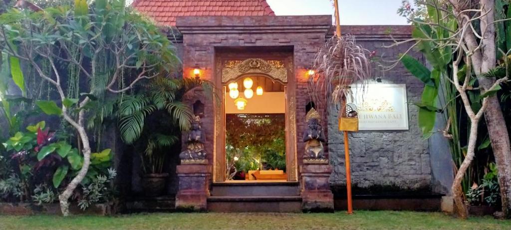 a building with a doorway in a yard with trees at The Jiwana Bali Resort in Ungasan