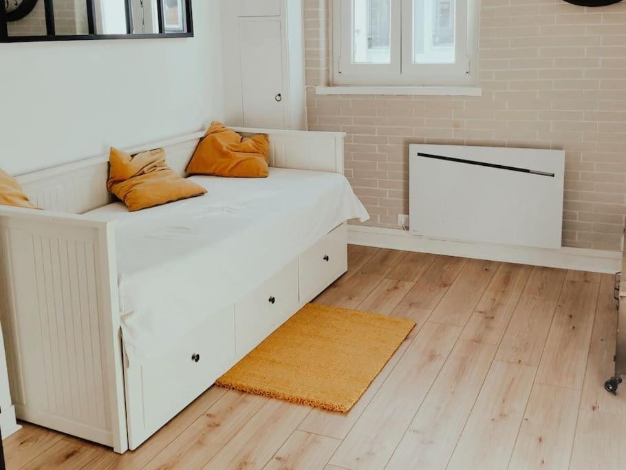een wit bed met oranje kussens erop in een kamer bij Les Coquelicots in Honfleur