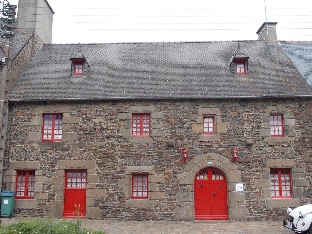 een oud stenen gebouw met rode deuren en ramen bij Suite Retour en Enfance in Dol-de-Bretagne