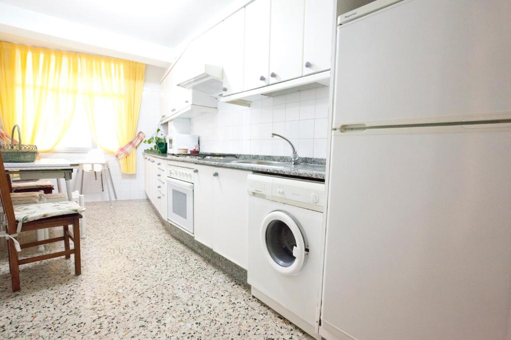 a white kitchen with a washer and dryer in it at Apartamento en Portonovo 200m de la Playa. + WIFI in Portonovo