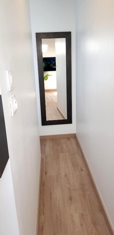 a mirror in a white room with a wooden floor at Escapade Niortaise - Studios climatisés hyper-centre de Niort in Niort