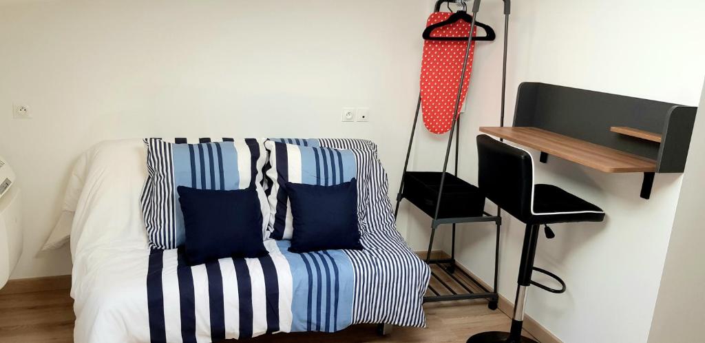 a room with a couch with blue pillows and a desk at Escapade Niortaise - Studios climatisés hyper-centre de Niort in Niort