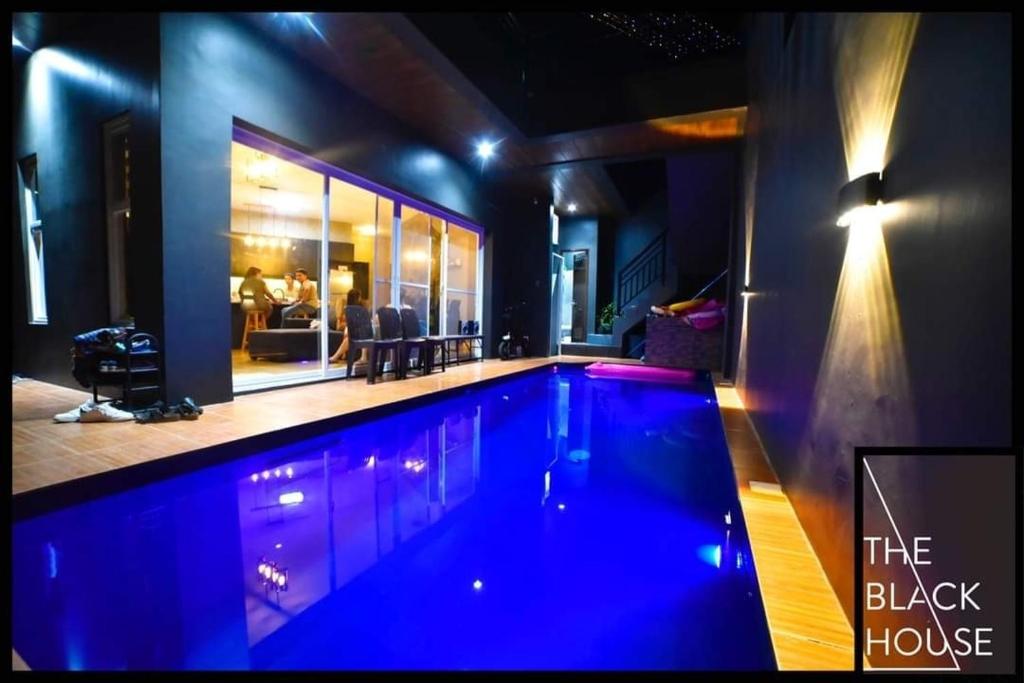 a swimming pool in a house with blue lighting at The Black House in Dulong Bayan