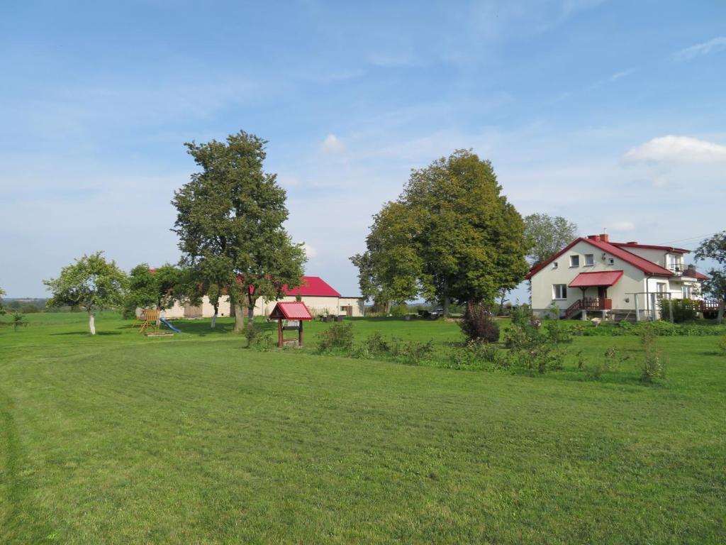 um campo com uma casa e árvores num campo em Agrocamp em Pawłówka
