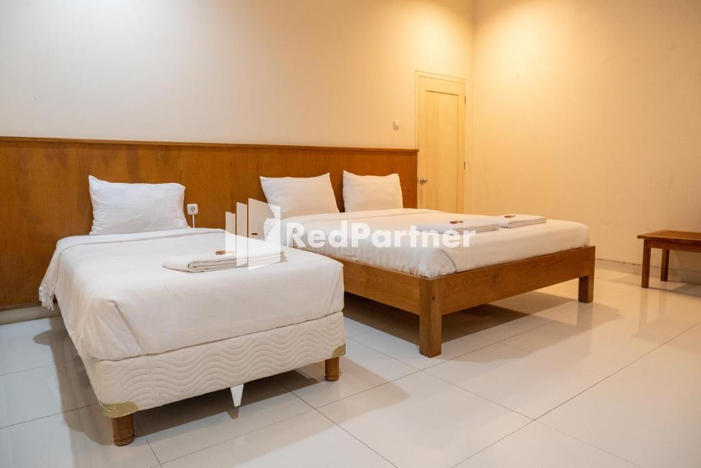 a bedroom with two beds with white sheets at Villa Dora Jogja Mitra RedDoorz near Malioboro Area in Sentool